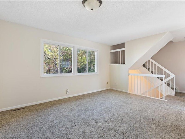 carpeted spare room with a textured ceiling