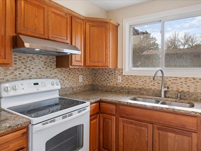 kitchen with light stone countertops, sink, tasteful backsplash, and electric stove