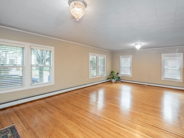 unfurnished room with ornamental molding, light hardwood / wood-style flooring, a baseboard heating unit, and an inviting chandelier