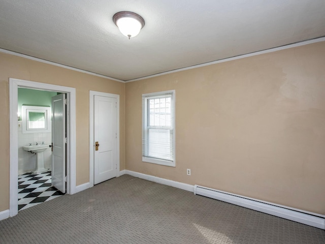 unfurnished bedroom with a closet, ensuite bath, sink, a baseboard radiator, and carpet floors