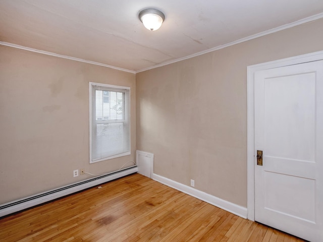 spare room with crown molding, hardwood / wood-style floors, and baseboard heating