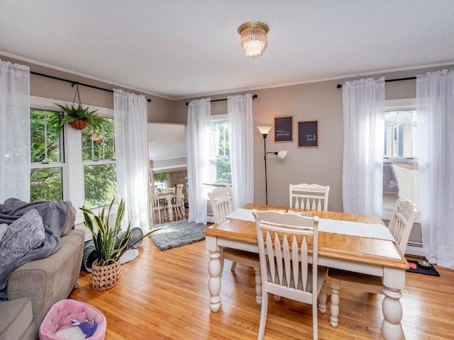 dining area featuring crown molding, hardwood / wood-style floors, and a baseboard heating unit