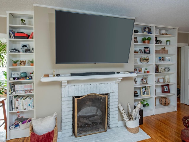 living room with crown molding, a textured ceiling, light wood-type flooring, and a brick fireplace