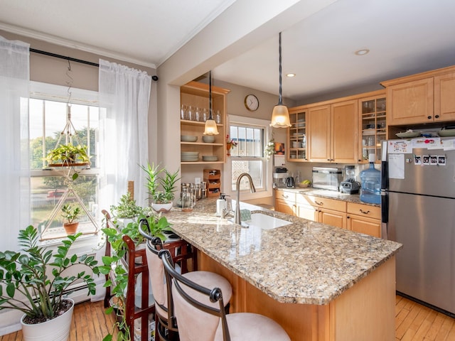 kitchen featuring light hardwood / wood-style floors, stainless steel fridge, sink, and plenty of natural light