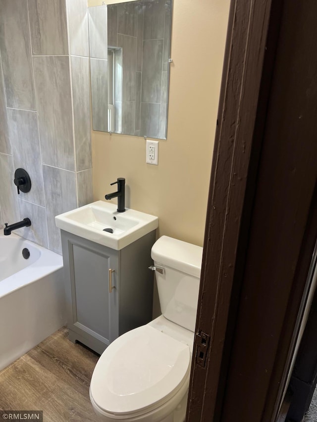 full bathroom featuring vanity, toilet, wood-type flooring, and tiled shower / bath combo