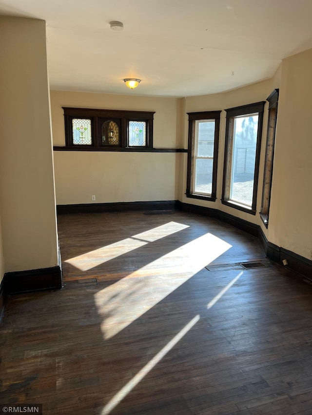 empty room featuring a wealth of natural light and dark hardwood / wood-style floors