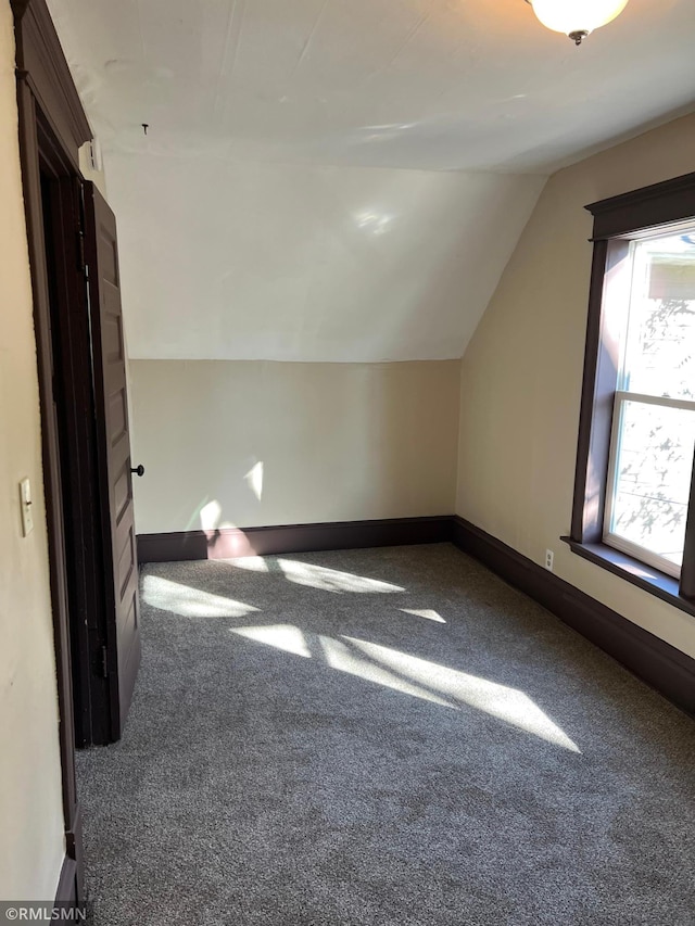 additional living space with lofted ceiling and dark colored carpet