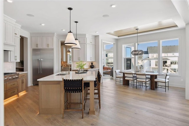 kitchen with light hardwood / wood-style flooring, appliances with stainless steel finishes, sink, and a center island with sink