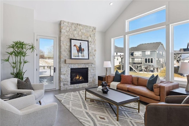 tiled living room featuring a stone fireplace, high vaulted ceiling, and plenty of natural light