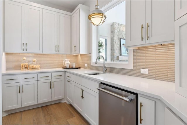 kitchen featuring dishwasher, sink, white cabinetry, light hardwood / wood-style floors, and pendant lighting