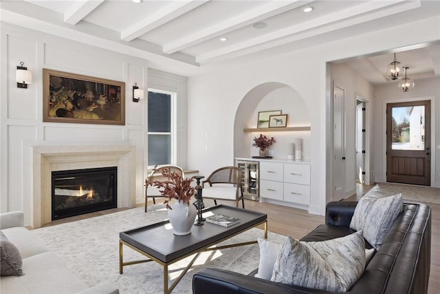 living room featuring a premium fireplace, light hardwood / wood-style flooring, wine cooler, and beamed ceiling