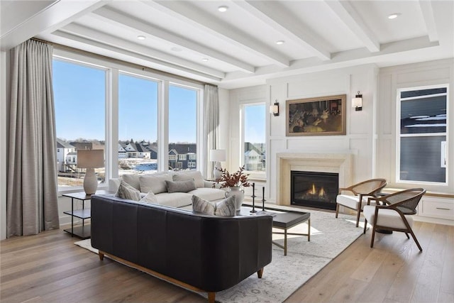 living room with beam ceiling, a premium fireplace, and wood-type flooring