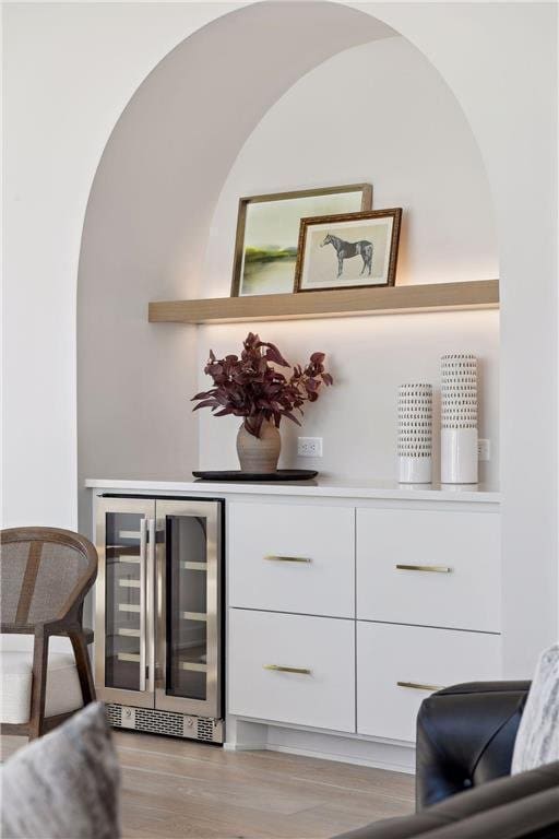 bar featuring white cabinetry, wine cooler, and light hardwood / wood-style floors