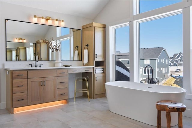 bathroom featuring vanity, vaulted ceiling, and a bath