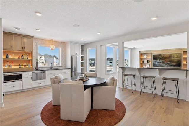 dining space featuring sink, light hardwood / wood-style flooring, and a textured ceiling