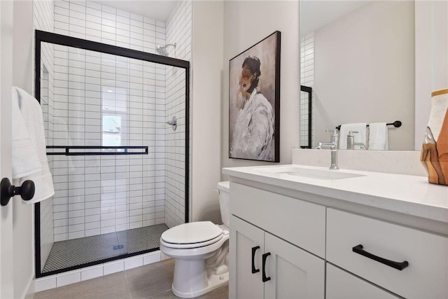 bathroom featuring toilet, a shower with shower door, vanity, and tile patterned floors