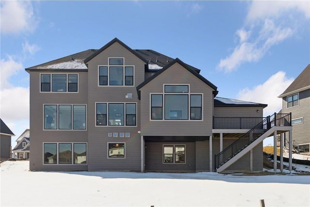 snow covered back of property featuring a wooden deck