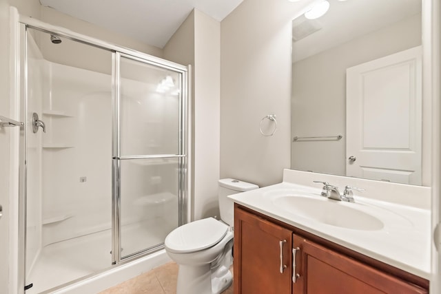 bathroom featuring tile patterned floors, vanity, a shower with shower door, and toilet