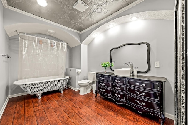 bathroom with hardwood / wood-style flooring, crown molding, toilet, and a tub to relax in