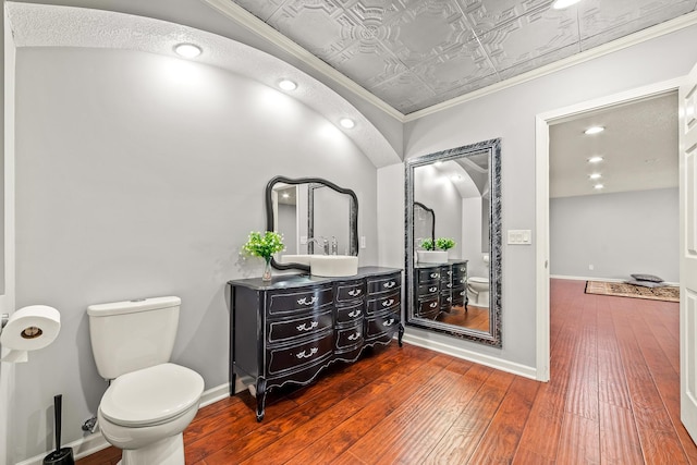 bathroom featuring vanity, toilet, wood-type flooring, and crown molding