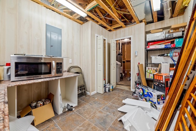 basement featuring wood walls, electric panel, and water heater