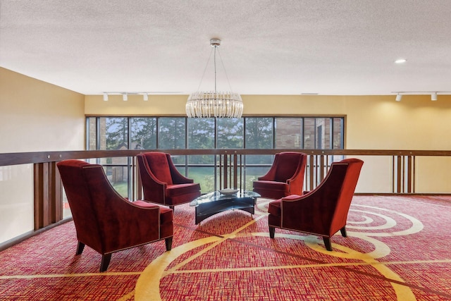 sitting room with a chandelier, a textured ceiling, rail lighting, and carpet floors