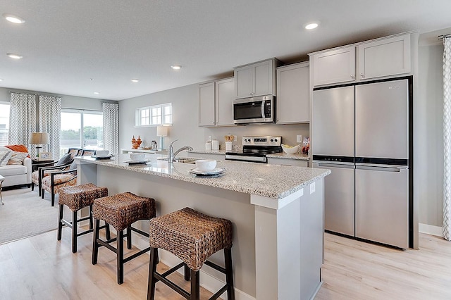 kitchen with a center island with sink, a breakfast bar, and appliances with stainless steel finishes