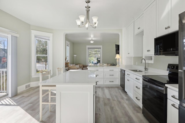 kitchen featuring light hardwood / wood-style flooring, kitchen peninsula, a healthy amount of sunlight, and black appliances