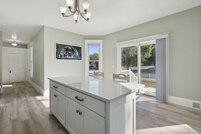 kitchen featuring white cabinetry, a center island, hanging light fixtures, and light wood-type flooring