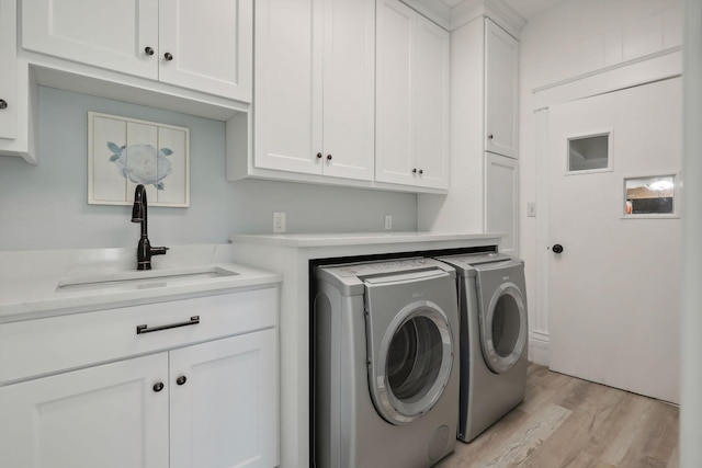 clothes washing area featuring sink, light hardwood / wood-style flooring, cabinets, and separate washer and dryer