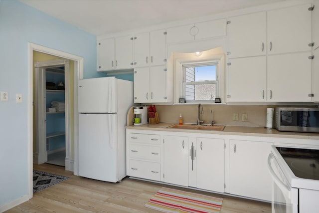 kitchen with white cabinetry, sink, light wood-type flooring, and white appliances