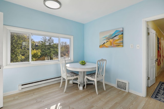 dining area with light hardwood / wood-style floors and a baseboard radiator