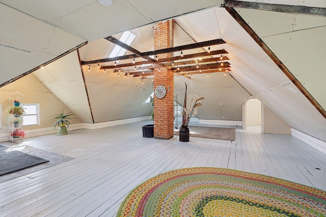 additional living space with vaulted ceiling with skylight and hardwood / wood-style flooring