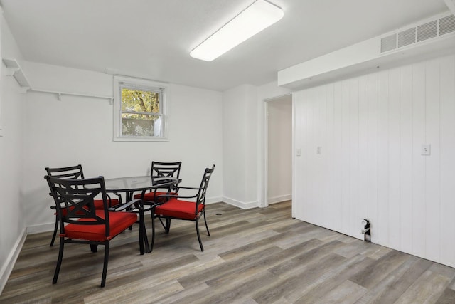 dining area with hardwood / wood-style flooring and wooden walls