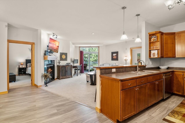 kitchen featuring light hardwood / wood-style flooring, sink, kitchen peninsula, and decorative light fixtures