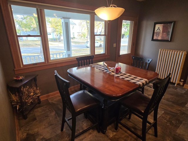 dining area with radiator heating unit, stone finish flooring, and baseboards