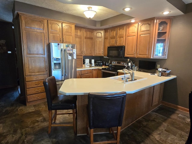 kitchen featuring stainless steel appliances, a peninsula, a kitchen bar, stone finish flooring, and light countertops