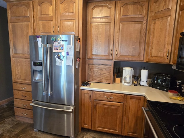 kitchen with electric range, brown cabinets, light countertops, and stainless steel fridge