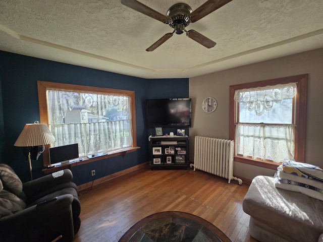 living area with radiator heating unit, hardwood / wood-style flooring, a textured ceiling, and ceiling fan