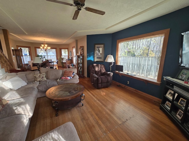 living room with wood-type flooring, baseboards, stairs, and ceiling fan with notable chandelier