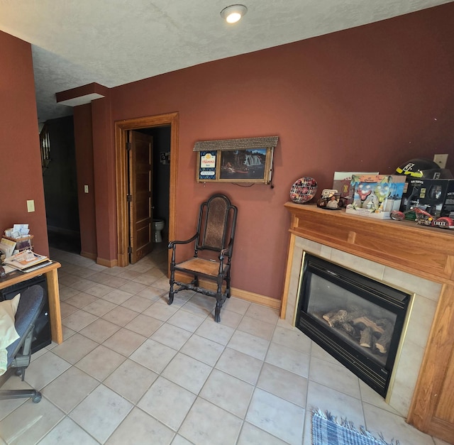 living room with baseboards, a glass covered fireplace, and light tile patterned floors