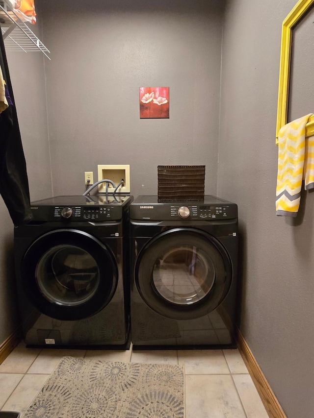 laundry room featuring separate washer and dryer, baseboards, tile patterned floors, and laundry area