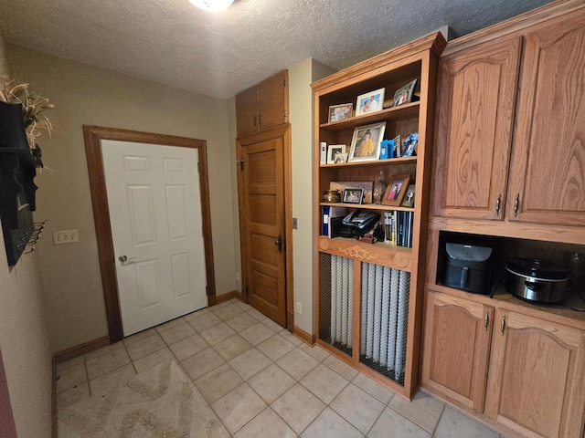 interior space with baseboards, a textured ceiling, and light tile patterned floors