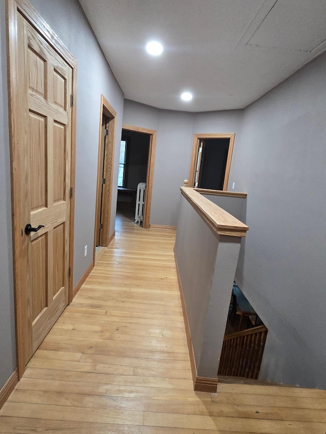 corridor featuring recessed lighting, light wood finished floors, baseboards, and an upstairs landing