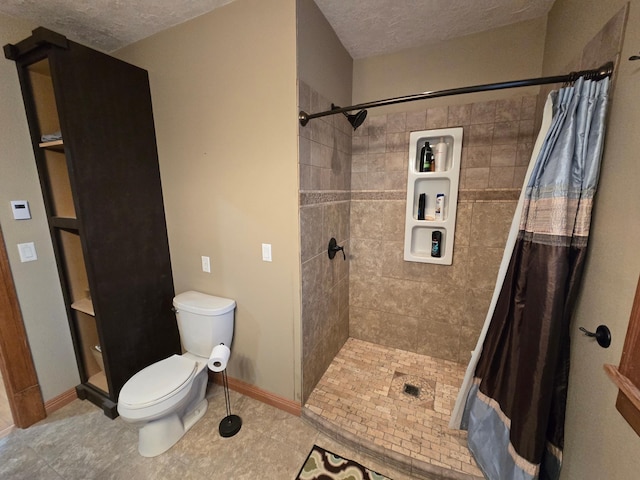 full bathroom featuring tile patterned floors, toilet, baseboards, a textured ceiling, and a stall shower