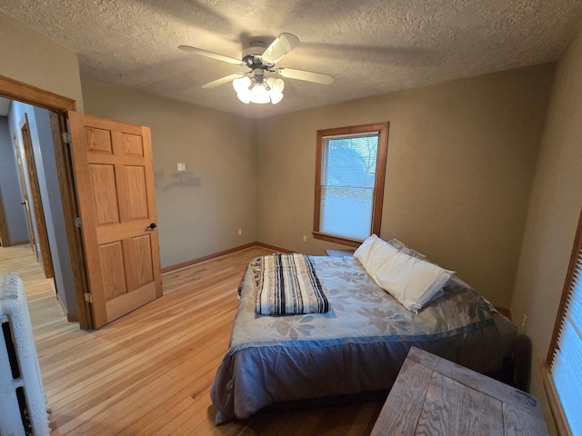 bedroom with a textured ceiling, light wood finished floors, and a ceiling fan