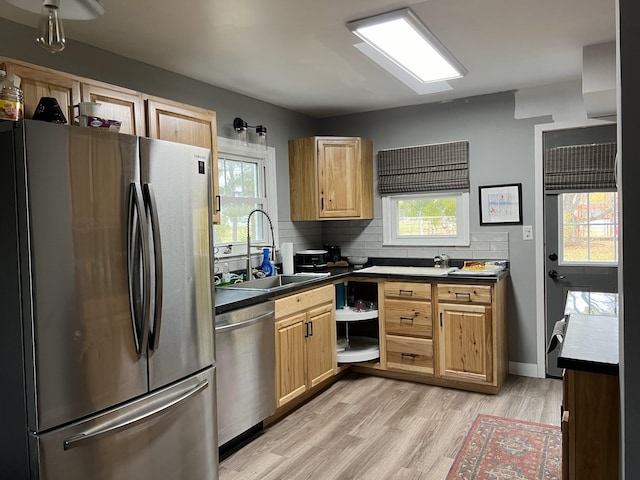 kitchen with backsplash, sink, appliances with stainless steel finishes, and light wood-type flooring