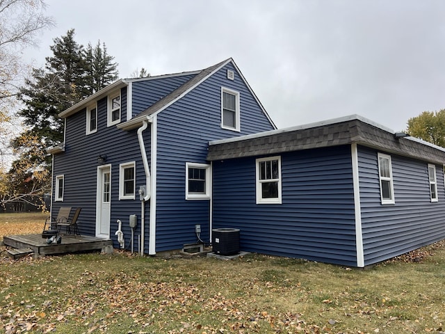 back of house featuring central AC, a wooden deck, and a lawn