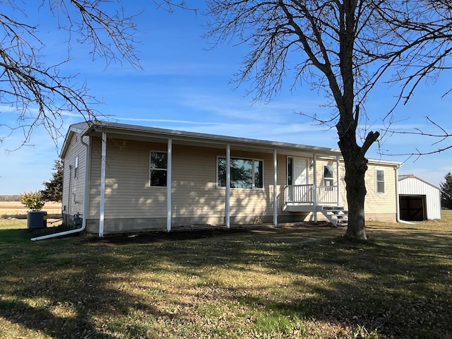 view of front of house featuring an outbuilding, covered porch, a front yard, and a garage