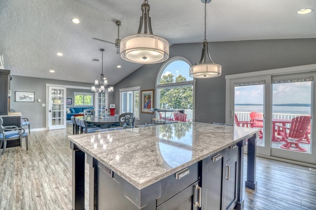 kitchen featuring a center island, vaulted ceiling, light hardwood / wood-style floors, and hanging light fixtures